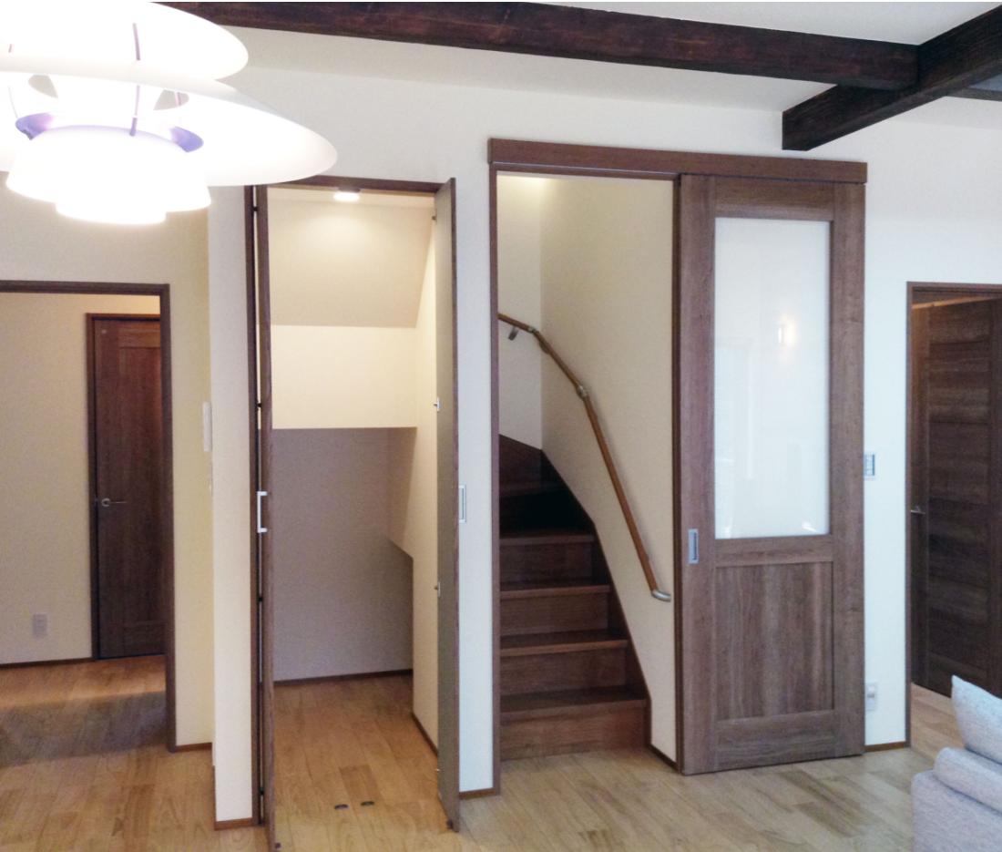 右から家族用玄関前の納戸への扉、階段、階段下を利用した収納スペース、一番左がゲスト用玄関からの扉